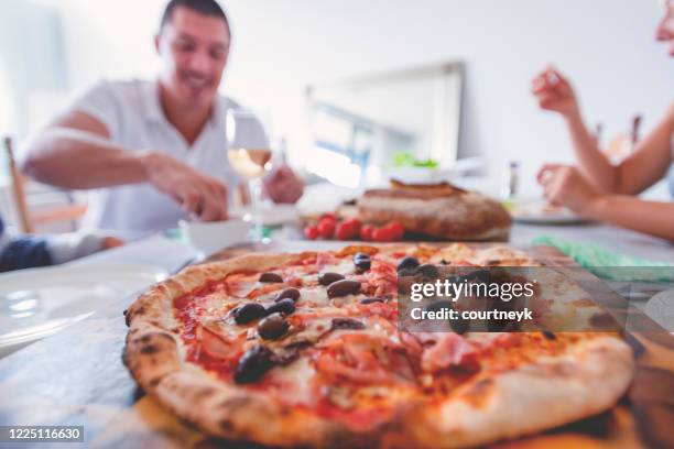 family or friends eating take away food. there is pizza, and bread on the table. - wine home delivery stock pictures, royalty-free photos & images