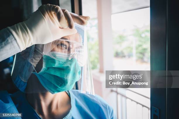 nurse having headache and tired from work while wearing ppe suit for protect coronavirus disease. - coronavirus nurse stock pictures, royalty-free photos & images