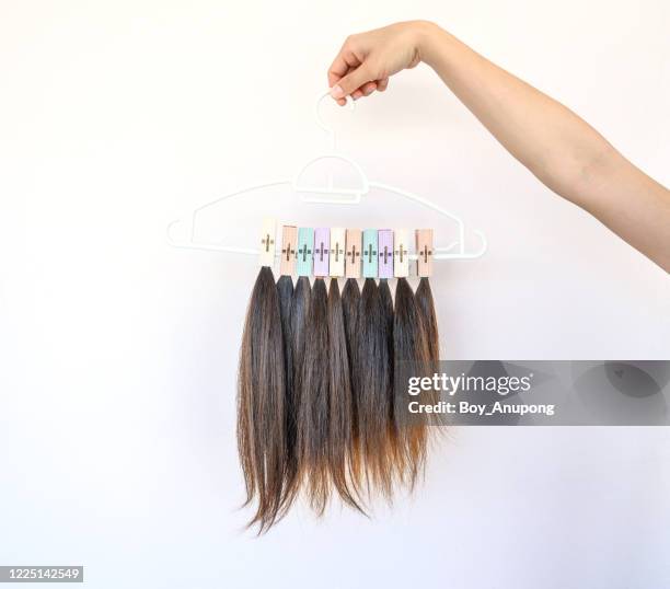 cropped view of someone hand holding a hanger with group of cutting hair for donation. - hand in hair ストックフォトと画像