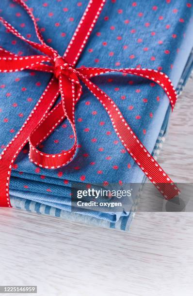 fabrics pile, dark blue with red polka dots pattern, red ribon on table background - ribbon sewing item stock pictures, royalty-free photos & images