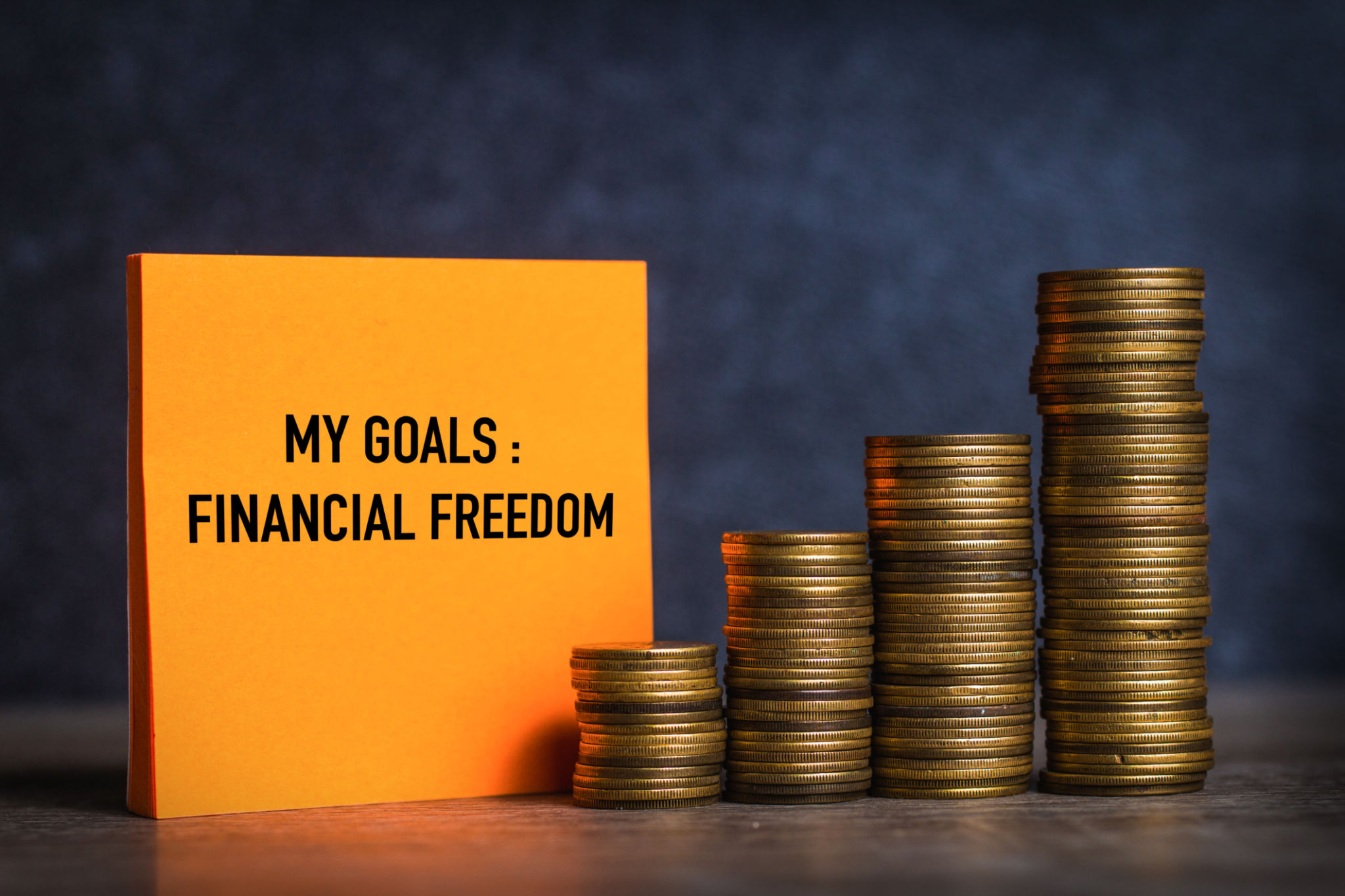 My goals and financial freedom written on orange note paper and coins stack My goals and financial freedom written on orange note paper and coins stack
