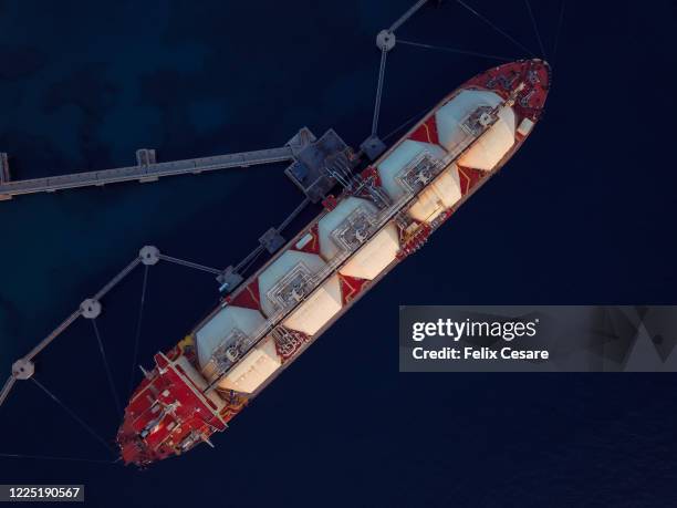 aerial top view of a liquefied natural gas (lng) tanker moored to the jetty - verkehrsgebäude stock-fotos und bilder