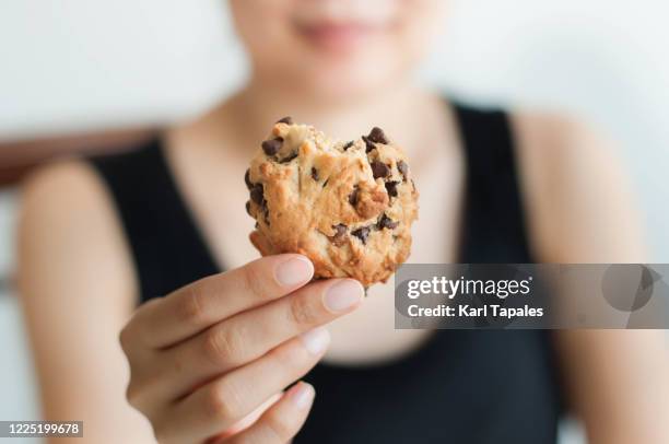 a young southeast asian woman is holding a freshly baked cookie - woman chocolate stock pictures, royalty-free photos & images