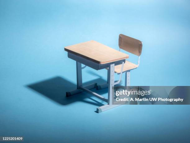 empty school desk on a blue background. conceptual. - klassenzimmer leer stock-fotos und bilder