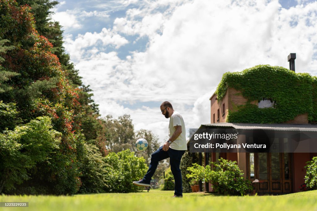 Man training soccer in his backyard