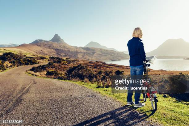 woman cycling in wester ross, scotland - scottish coat stock pictures, royalty-free photos & images
