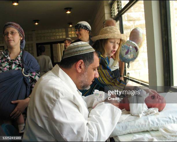 Un rabbin effectue la circoncision d'un enfant dans la colonie juive de Beit Hadassah à Hébron, le 23 juin 2003. AFP PHOTO SIMLHA LHMOULEVITCH A...