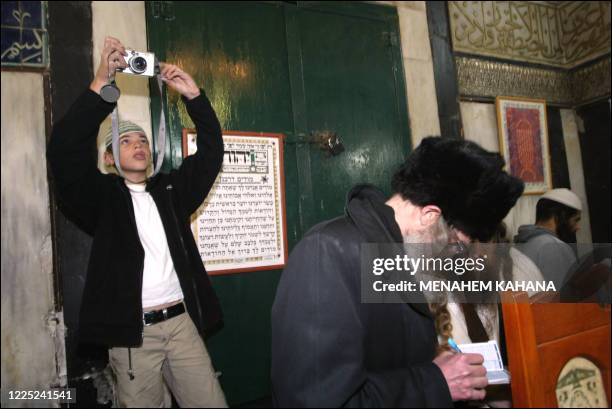 Shilo Benyizhak prend des photos le 28 novembre 2003 lors d'une cérémonie de circoncision au caveau des Patriarches à Hébron. AFP PHOTO MENAHEM...