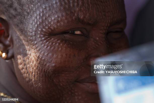 Southern Sudanese woman from Nuer tribe shows her registration card as she waits in a line outside a polling station in Bentiu, capital of...