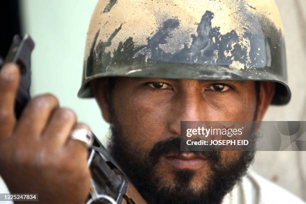 Libyan fighter loyal to the National Transitional Council takes cover behind a house close at the frontline during fighting against strongman Moamer...