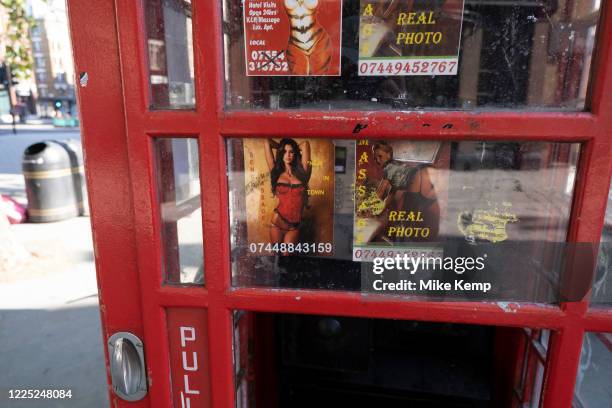 Public telephone box which has sex cards tacked up inside on 25th June 2020 in London, United Kingdom. These advertising cards for prostitutes are...