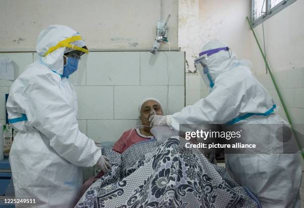 July 2020, Egypt, Giza: Medics wearing personal protective equipment put an oxygen mask to a coronavirus patient at the 6th of October Central...
