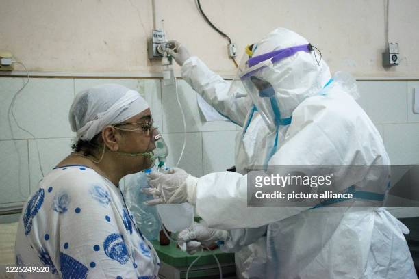 July 2020, Egypt, Giza: Medics wearing personal protective equipment put an oxygen mask on a coronavirus patient at the 6th of October Central...