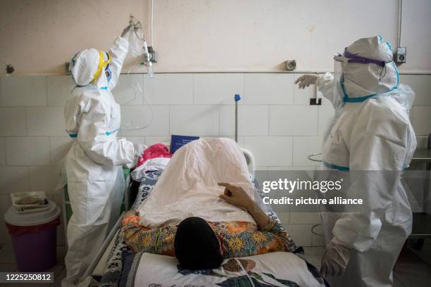 July 2020, Egypt, Giza: Medics wearing personal protective equipment tend to a coronavirus patient at the 6th of October Central Hospital, which is...