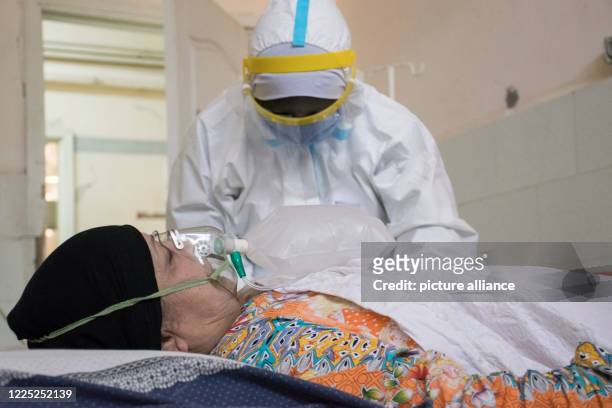 July 2020, Egypt, Giza: A medic wearing personal protective equipment tends to a coronavirus patient at the 6th of October Central Hospital, which is...