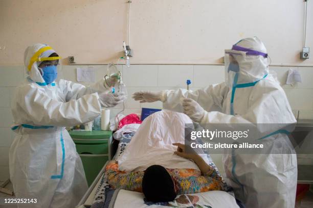 July 2020, Egypt, Giza: Medics wearing personal protective equipment tend to a coronavirus patient at the 6th of October Central Hospital, which is...