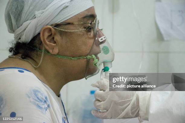 July 2020, Egypt, Giza: A medic tends to a coronavirus patient breathing through an oxygen mask, at the 6th of October Central Hospital, which is...