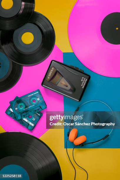 top view of vinyl records, cassettes, a walkman and headphones with orange foam, musical reproduction elements of the 70s, 80s and 90s with colorful background design - lp fotografías e imágenes de stock