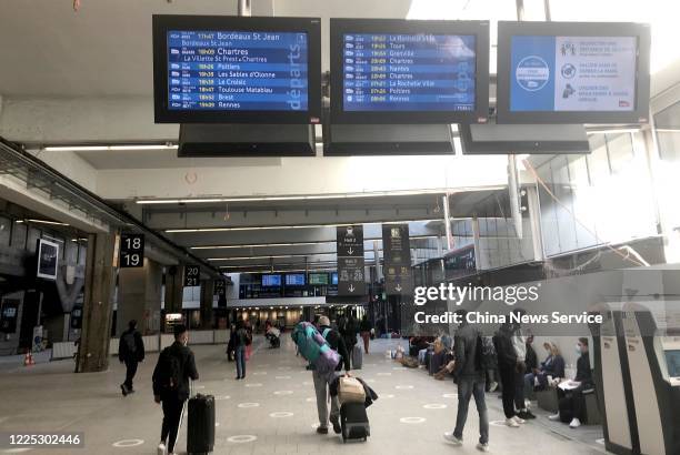 People wearing face masks walk at Gare Montparnasse railway station on May 16, 2020 in Paris, France. France started to ease restrictions on movement...