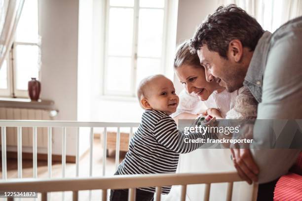 mère et père avec le fils à la maison dans le berceau - chambre nouveau né famille photos et images de collection