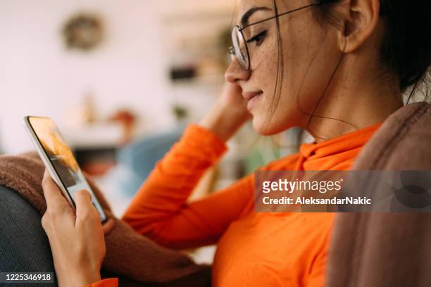 what's online? - young woman using smartphone at home stock pictures, royalty-free photos & images