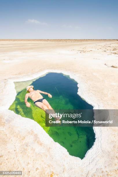 man bathing in a pond of salt flat, danakil depression, afar, ethiopia - danakil depression stock-fotos und bilder