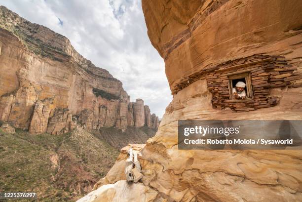 priest looking out from rock-hewn abuna yemata guh church,tigray region, ethiopia - abuna yemata guh church stock pictures, royalty-free photos & images