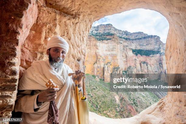 orthodox priest holding the hand cross, abuna yemata guh church,tigray region, ethiopia - abuna yemata guh church stockfoto's en -beelden