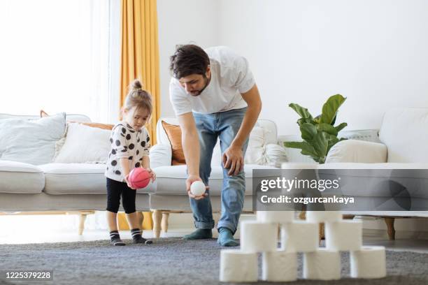 happy young father with little girl having fun with some toilet paper rolls - kids bowling stock pictures, royalty-free photos & images