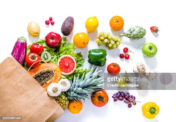 bolsa de papel llena de varios tipos de frutas y verduras sobre fondo blanco - fruta tropical fotografías e imágenes de stock