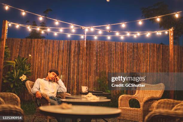 tiener rustenin de achtertuin patio luisteren naar muziek - covid-19-serie - snoerverlichting stockfoto's en -beelden