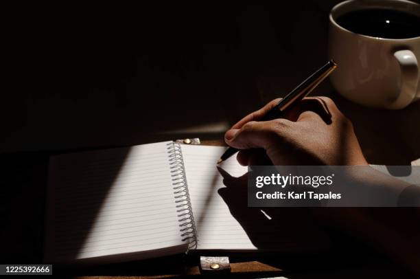 a young person who is writing a journal over a cup of coffee - hand pen photos et images de collection