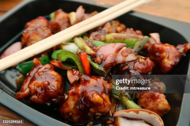 bild von würzigen kung pao huhn zumstich mahlzeit in schwarzem kunststoff einwegbehälter mit holzesstäbchen, zwiebel, rote und grüne paprika, erhöhte ansicht - kung pao huhn stock-fotos und bilder