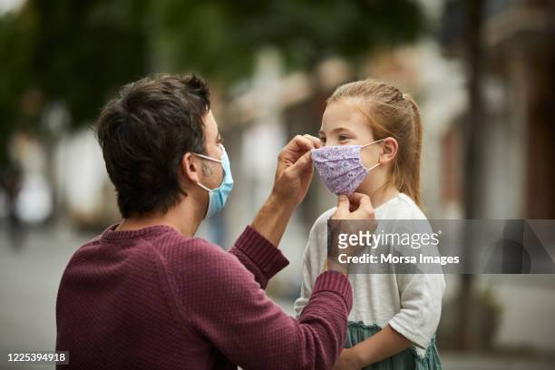 father putting home made face mask on little daughter - protective face mask stock pictures, royalty-free photos & images