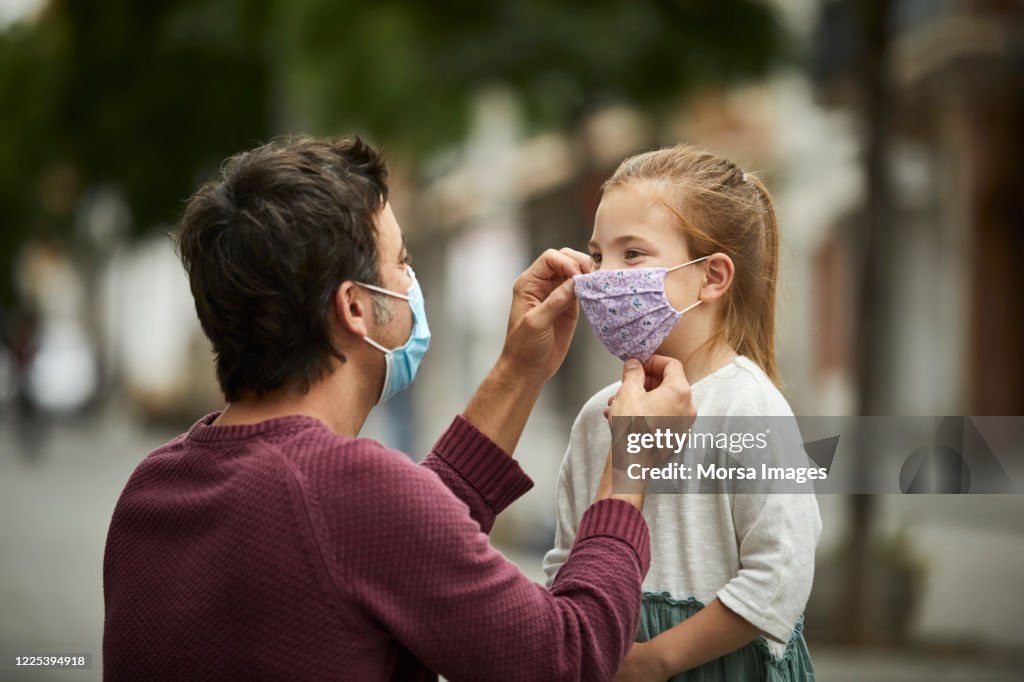 Father Putting Home Made Face Mask on Little Daughter