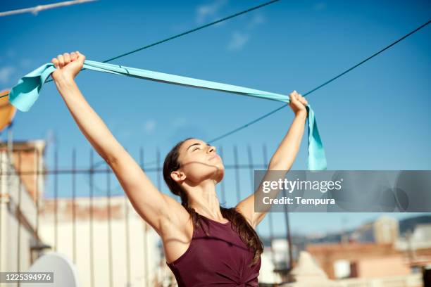 eine junge frau, die mit einem gummiexpander strectching. - gummiband stock-fotos und bilder