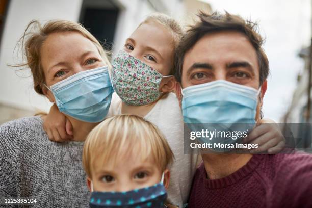 real family taking a selfie together while wearing protective face masks - real people lifestyle and family foto e immagini stock