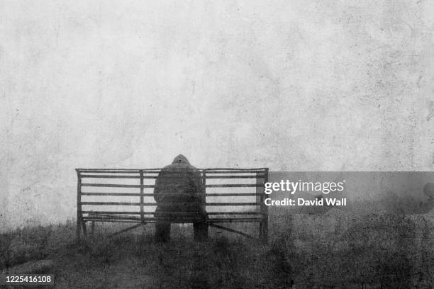 a mental health concept of mysterious figure back to camera, sitting on a bench alone. with a grunge, textured edit. - selbstmord stock-fotos und bilder