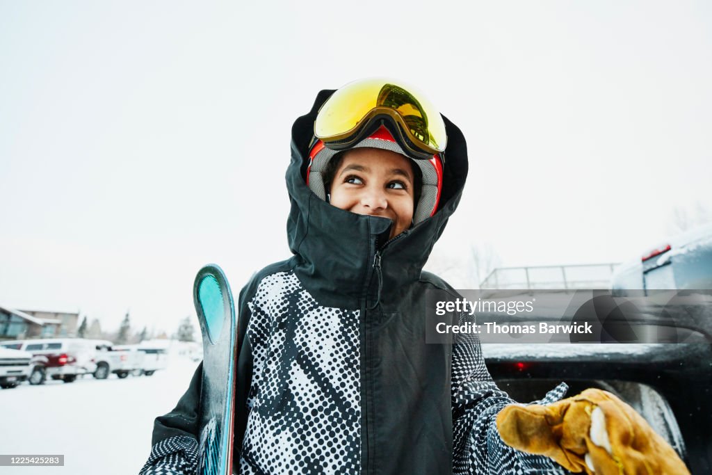 Smiling boy standing in parking lot of ski area before going skiing