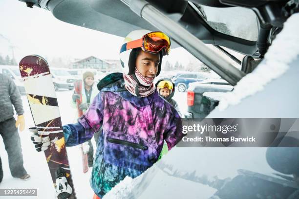 Teenage boy getting gear out of car before skiing with family