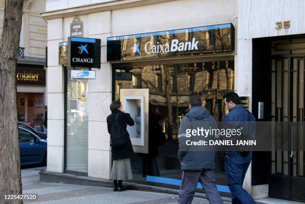 Une personne prend de l'argent, le 15 février 2002 avenue des Gobelins à Paris, à un guichet de la banque Caixa. CaixaBank a indiqué le 14 février...