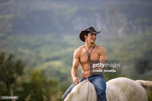 sonriendo muscular sin camisa joven adulto hombre montando a caballo - sin camisa fotografías e imágenes de stock