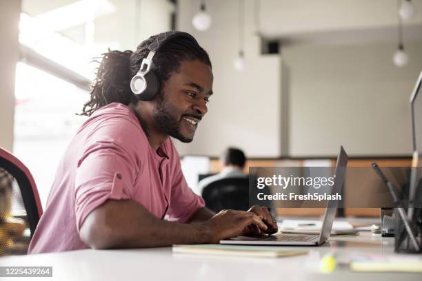 modern businessman with headphones working on his laptop - man pink stock pictures, royalty-free photos & images