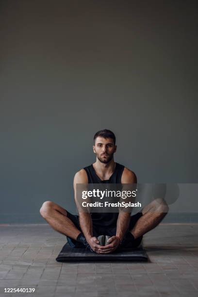 young handsome muscular man stretching his body after a workout - lotus position stock pictures, royalty-free photos & images