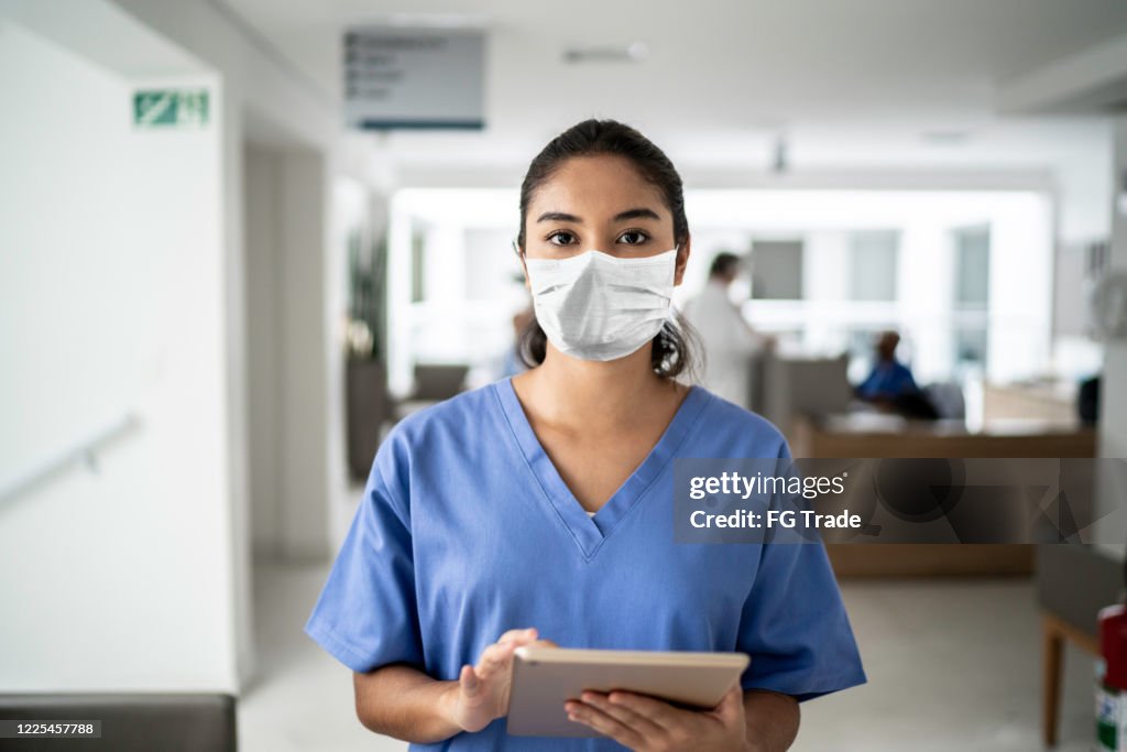 女性護士在醫院拿著數位平板電腦使用防護面罩的肖像