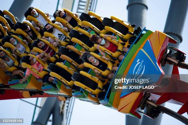 Visitors wearing face masks enjoy a ride on the reopening day of the Spanish resort and theme park complex PortAventura World Resort in Salou on July...