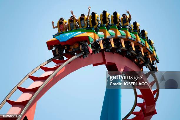 Visitors wearing face masks enjoy a ride on the reopening day of the Spanish resort and theme park complex PortAventura World Resort in Salou on July...