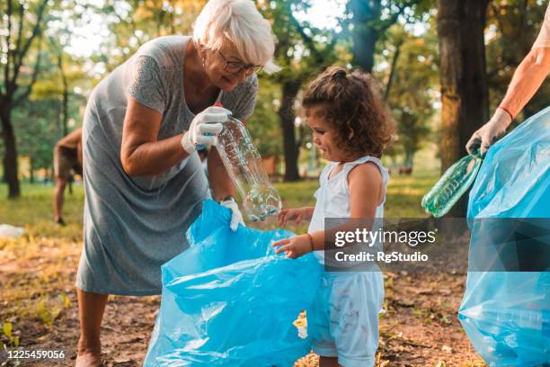 little girl cleaning the park with her grandma - volunteers cleaning public park stock pictures, royalty-free photos & images