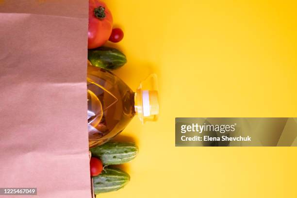 paper bag with vegetables.cucumbers, tomatoes, vegetable oil, eggs isolated on yellow background.food supplies crisis food stock for quarantine.food delivery, donation, coronavirus.tape measure. - home delivery stock pictures, royalty-free photos & images