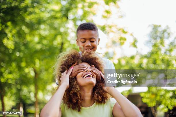 afro junge spielen peekaboo mit mama - augen zuhalten stock-fotos und bilder